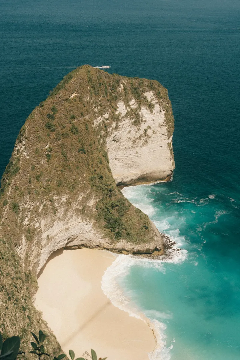 Turquoise ocean meeting the green cliffs of Kelingking Beach in Bali